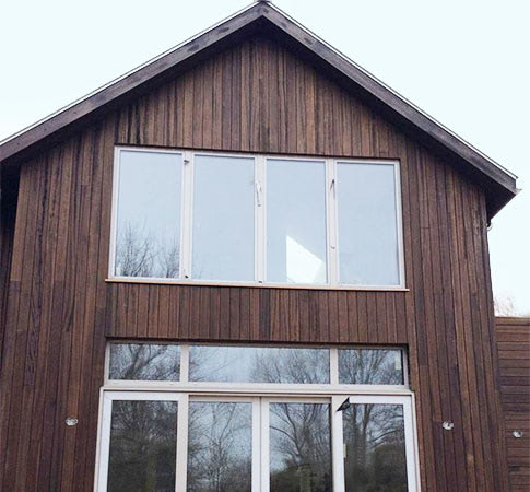 This custom building project with wood rainscreen siding shows off good looks with deep brown-black stain and dark graining