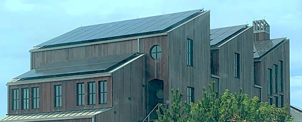 Modern three peaked roofline in Cape Cod with large windows, solar panels, and Ipe Wood Rainscreen Wood Siding. 