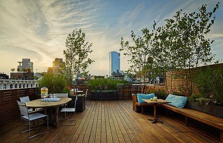 Natural hardwood rooftop deck with planters, benches and privacy wall courtesy of Organic Gardener NYC