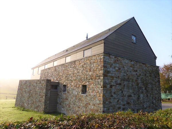 Trespa Pura NFC siding in Aged Ash blends with natural stone on this contemporary home