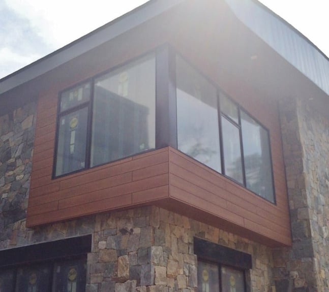 Trespa pura siding adds warm look of wood to stone facade