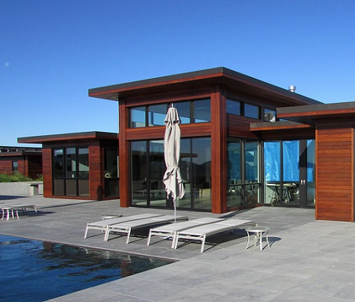 Warm Ipe rainscreen exterior looks over a cool stone deck  and pool