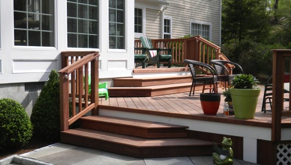 A bi-level deck and stairs on a house made with cumara decking and an ipe railing system, with planters and patio furniture
