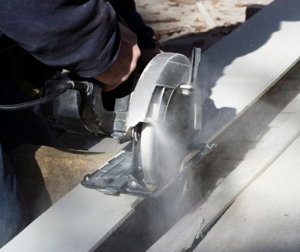 Example image of a contractor cutting composite wood siding plank causing potentially hazardous dust