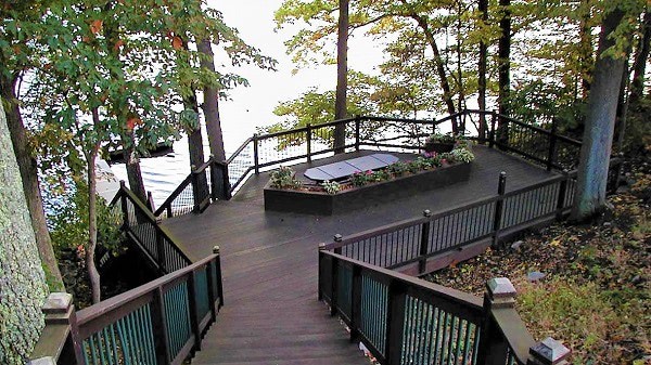 A multilevel deck built up a hillside with stairs leading to dining and relaxing levels with built in seating, then down to the dock in the river. and relaxing. 