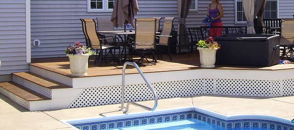 Raised hardwood deck with hot tub and dining area by pool