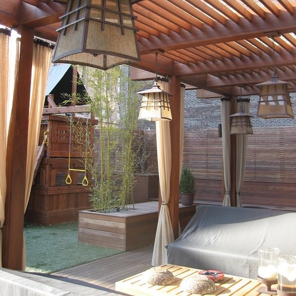 Ipe hardwood  pergola with lanterns, drapes, planters and a playscape
