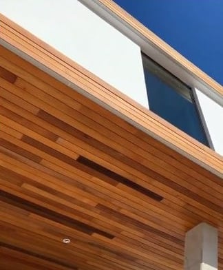 The Garapa wood soffit makes a warm, inviting natural surround to the entranceway for this wood rainscreen and stucco home.